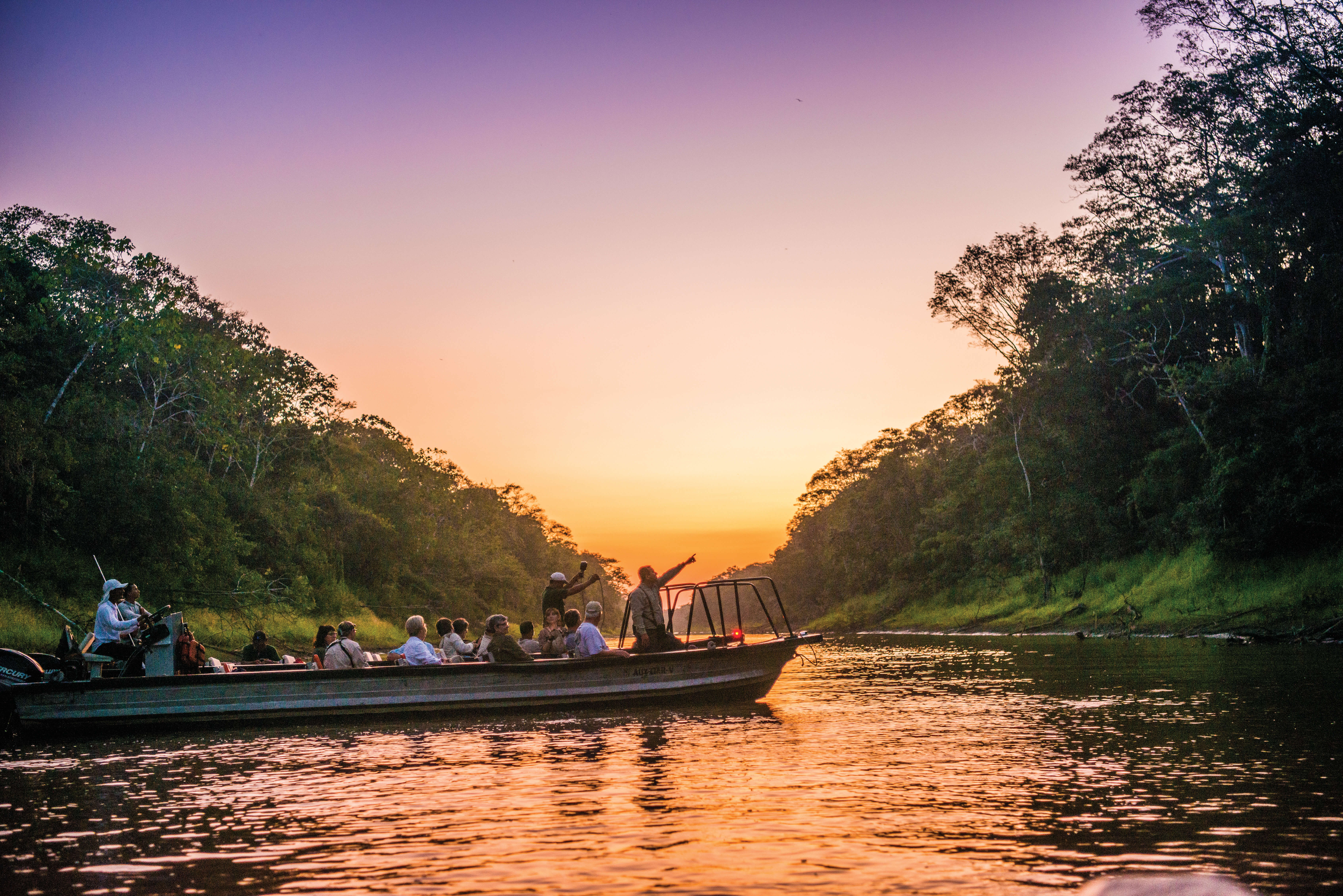 A skiff full of passengers exploring the Amazon at dusk